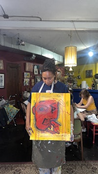 a woman holding up a painting in a room