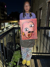 a woman holding a painting on a balcony