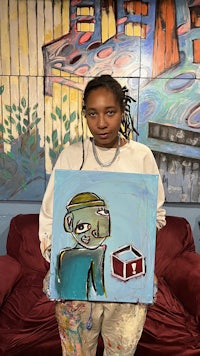 a girl holding up a painting of a box