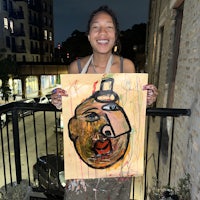 a woman holding a painting on a balcony