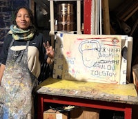 a woman in an apron standing next to a painting