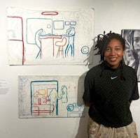 a young woman standing in front of her artwork