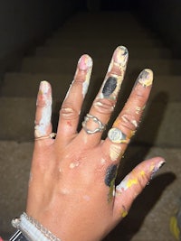 a person's hand with paint on it and a ring on it