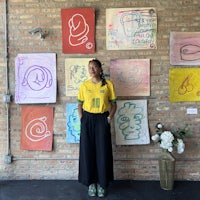 a woman standing in front of a wall full of drawings