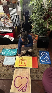 a woman kneeling on the floor with several pieces of paper in front of her