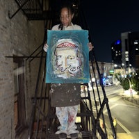 a woman holding a painting on a stairway