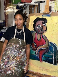 a woman in an apron standing next to a painting