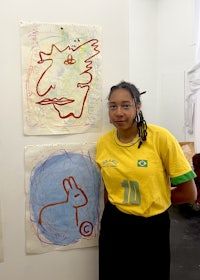 a young girl standing in front of a wall full of drawings