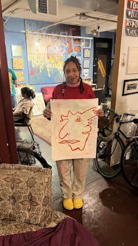 a girl holding up a drawing in a room