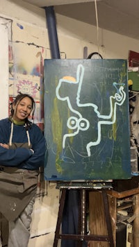 a woman standing in front of an easel with a painting on it