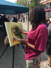 a woman with dreadlocks painting on a canvas