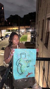 a woman holding up a painting on a balcony