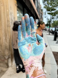 a person holding up a painted hand on a sidewalk